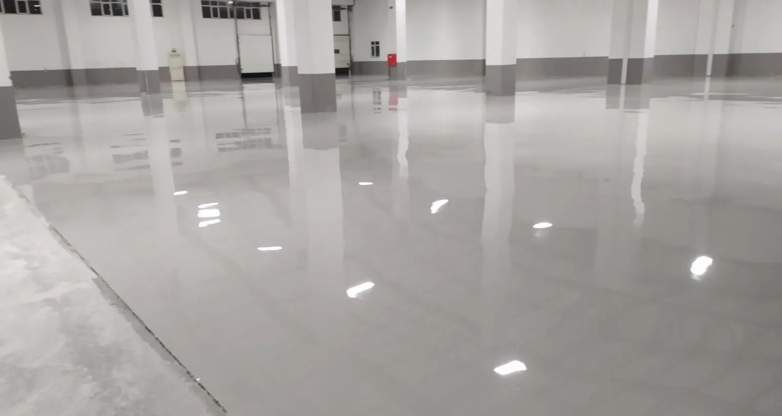 Hero: geniş açı fabrika zemini, parlak epoksi yüzey, çizgi işaretlemeler